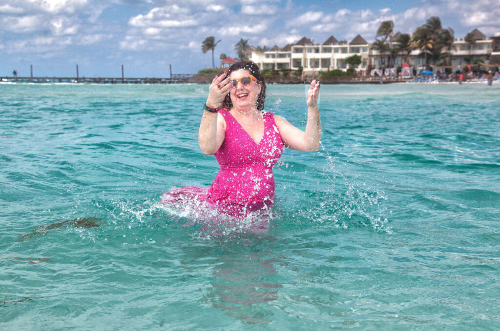 A woman in a pink dress plays in the Caribbean Sea