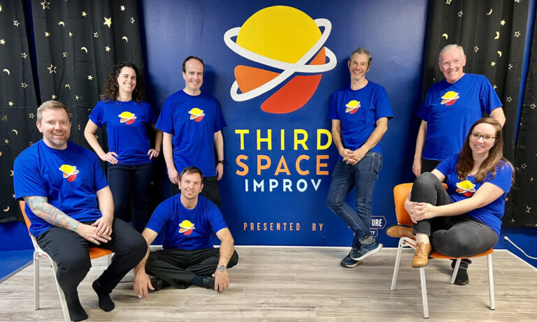 Peformers in Third Space Improv t-shirts on stage in front of the Third Space Improv logo