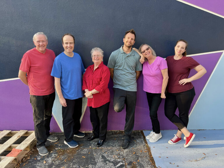 Improv performers pose in front of the theatre